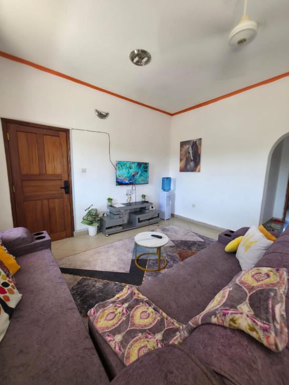 a living room with a couch and a tv at Breezy hideaway malindi 2br in Malindi