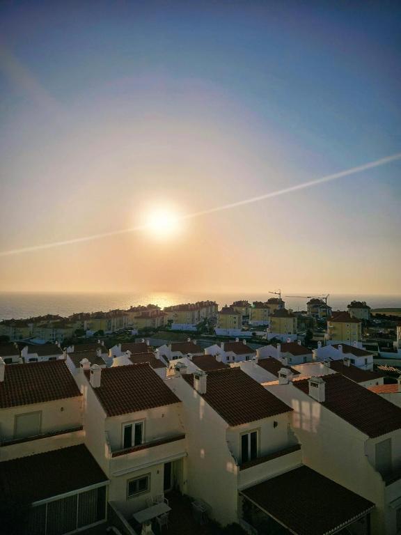 a sunset over roofs of houses in a city at Ericeira Beach Apartment in Ericeira