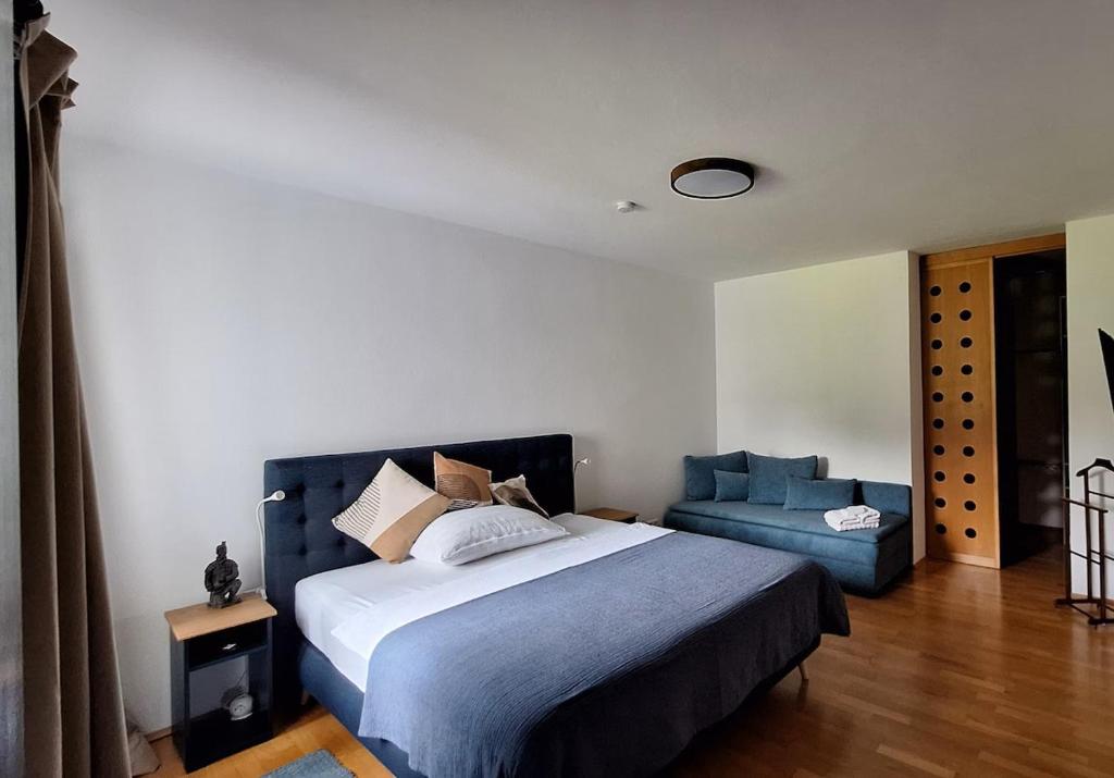a bedroom with a large bed and a blue couch at Gästehaus FaRitz in Knittelfeld