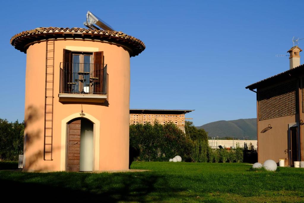 a small building with a balcony on a grass field at La Maraviglia in Foligno