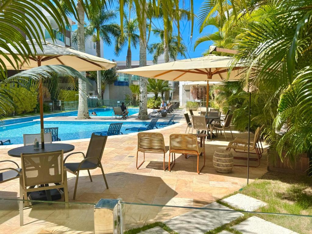 a patio with tables and chairs next to a pool at Excelente Apto no condomínio Boulevard in Bombinhas