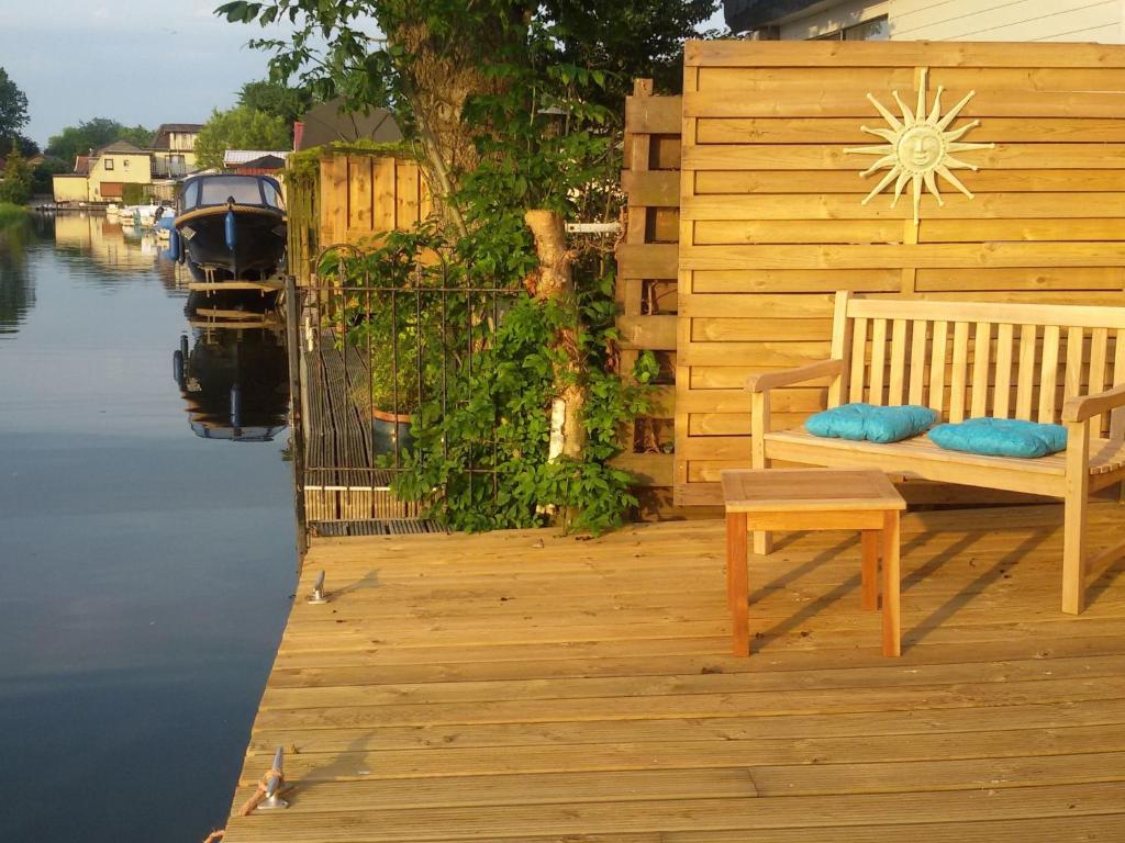 a wooden deck with a bench sitting on the water at Apartment Haus Jule by Interhome in Wervershoof
