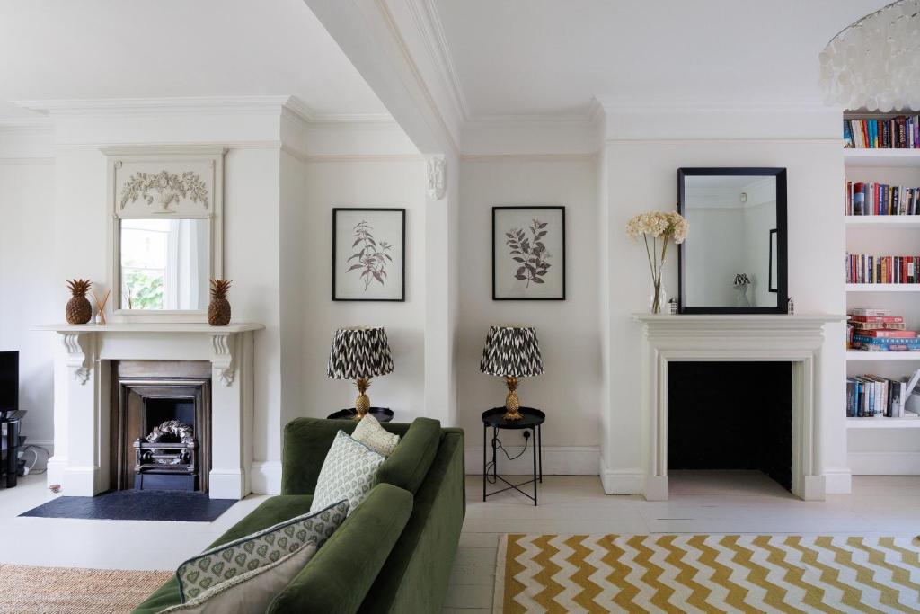 a living room with a green couch and a fireplace at Stylish, Spacious, Oxford Townhouse, Driveway parking in Oxford