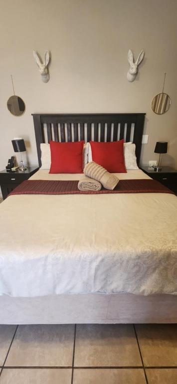 a bedroom with a large bed with two red pillows at RoomsAtRoseAve19 in Kuruman
