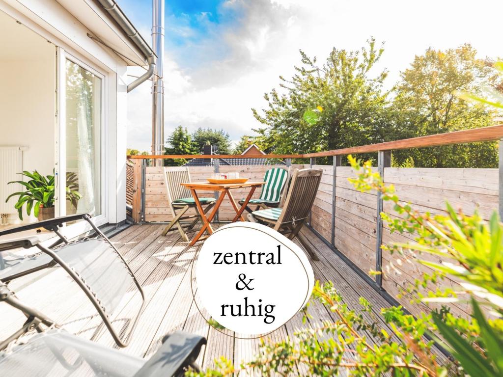 a patio with a table and chairs on a deck at Casa Ueberall - Ruhige DG-Ferienwohnung für 2 Erwachsene in Burg - Balkon mit Abendsonne, hochwertige Ausstattung, überdachter E-Bike-Stellplatz, Nähe zur Altstadt & Restaurants in Fehmarn