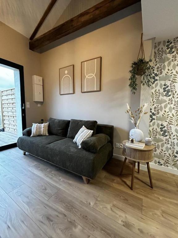 a living room with a black couch and a table at L'arbre de soie - l'acacia in Vouillé