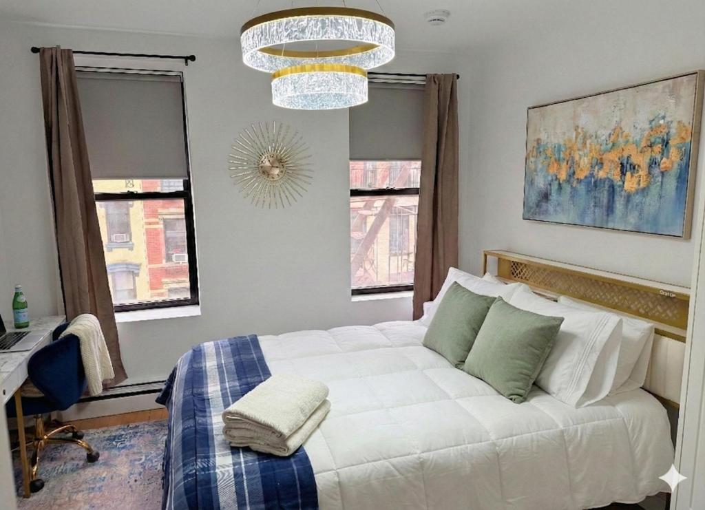a bedroom with a white bed and a chandelier at Comfortable 2BR & 2 Bath Apt in Downtown NYC in New York