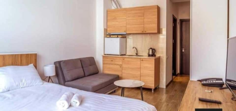 a bedroom with a bed and a chair and a kitchen at Tribu in Bakuriani
