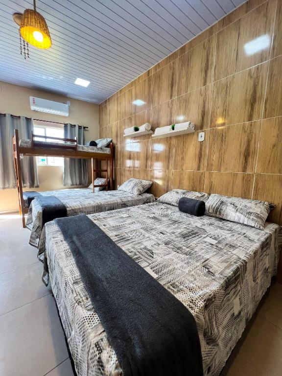 two beds in a room with wooden walls at Apartamento juçara Lençóis in Barreirinhas