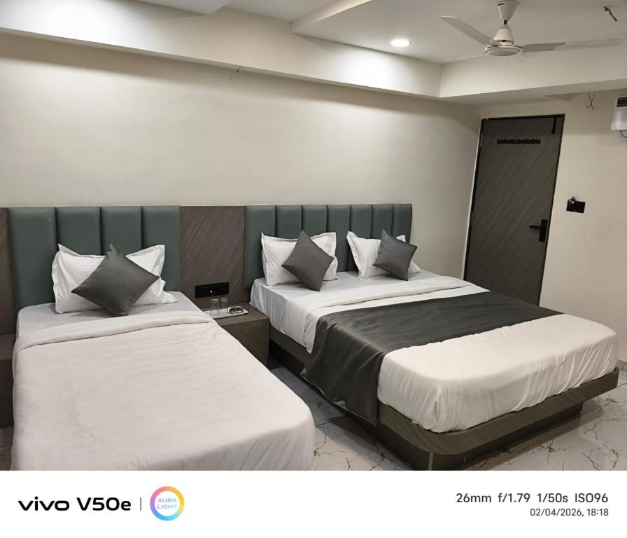 two beds in a hotel room with two beds at Hotel 7 CR in Ahmedabad