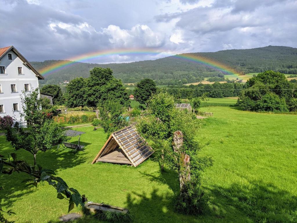 Ein Regenbogen am Himmel über einem Feld mit einem Haus in der Unterkunft Hanauerhof in Schönsee