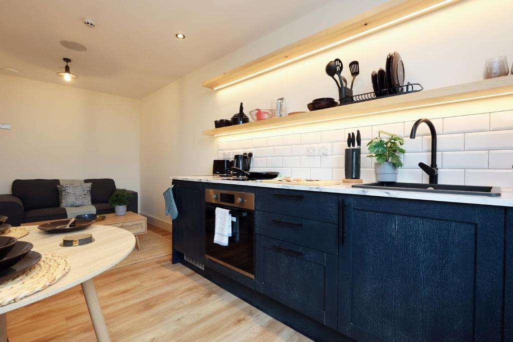 a kitchen with black cabinets and a living room at The Swansea Central Hall 1 Bed Room Apartment in Swansea
