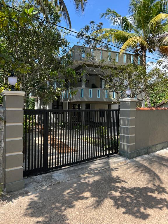 an iron gate in front of a house with palm trees at Belgi Guest House in Balapitiya