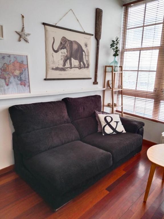 a black couch in a living room with a picture of an elephant at María II in Ferrol