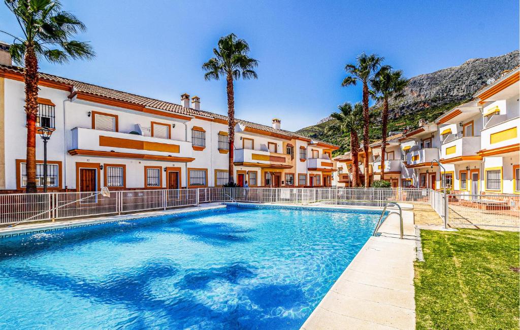 a swimming pool in front of a building with palm trees at La Escapadita in Benaoján