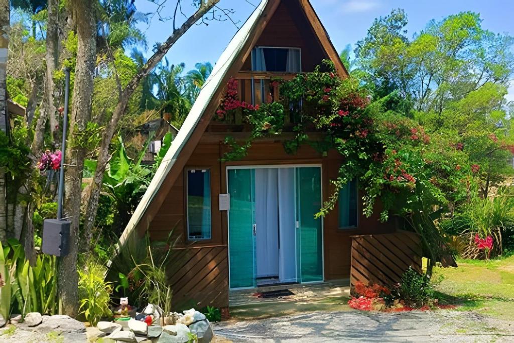 a cottage with a green door and flowers at Chalé Primavera Rosa com piscina in Penha