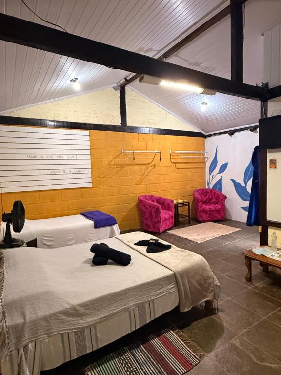 a room with two beds and two pink chairs at Hotel da Vila in Nova Friburgo