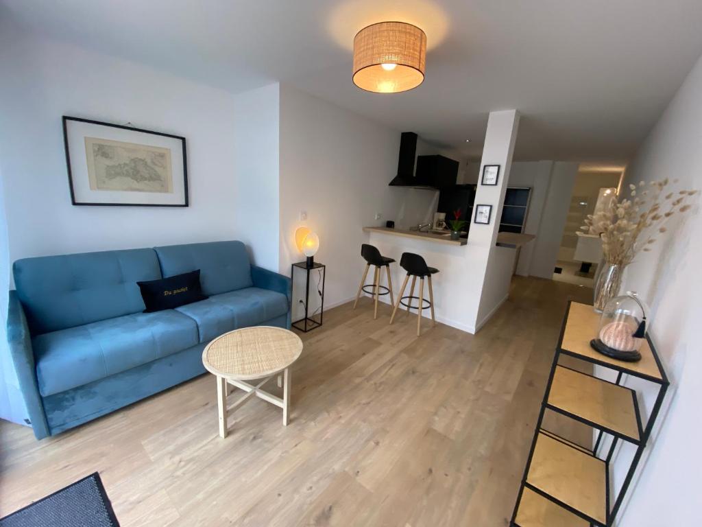 a living room with a blue couch and a table at Studio Dour avec terrasse à proximité des plages in Étel