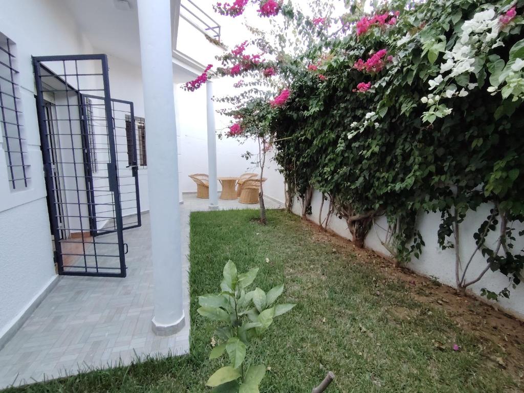 a garden with pink flowers next to a white building at Villa Perle Bleu in Saïdia