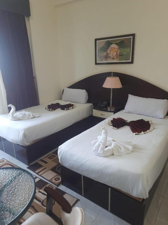 two beds in a hotel room with towels on them at Le-Printemps Hotel in Suez