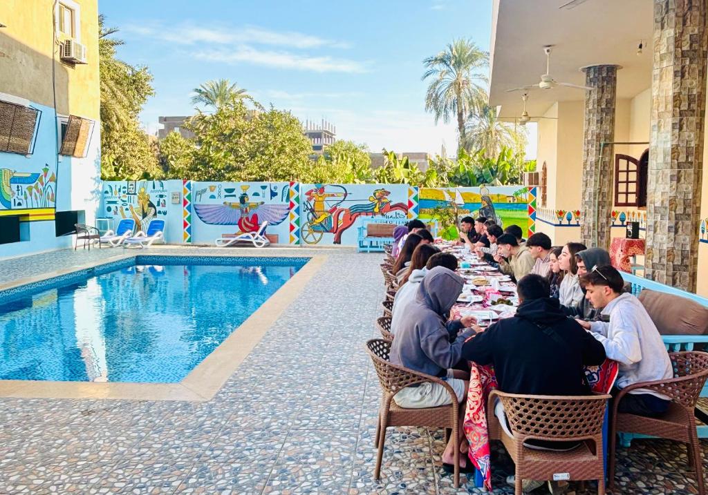 a group of people sitting at a table by a pool at Luxor View Hotel in Luxor