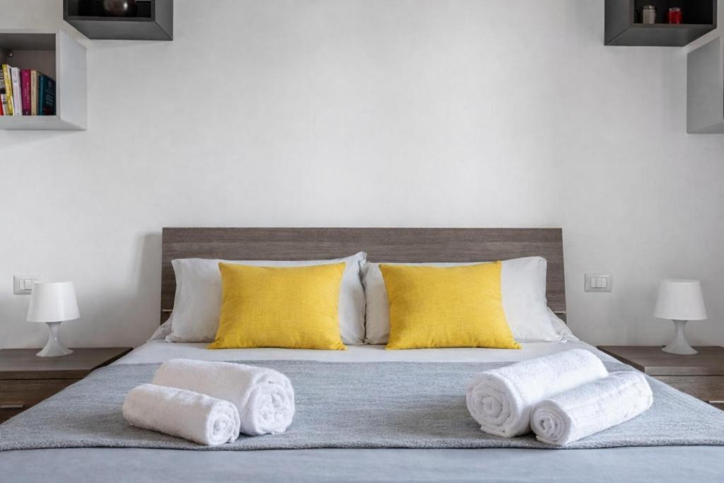 a bed with yellow pillows and towels on it at Sarca 11th Floor in Milan