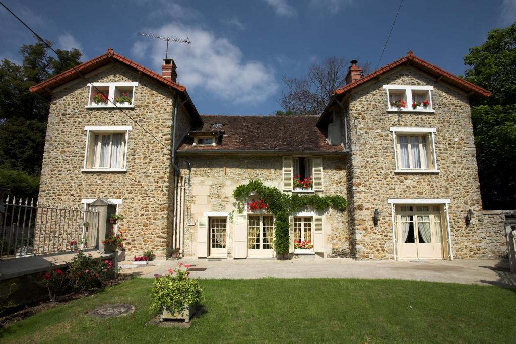 a large stone house with two windows and a yard at Demeure de la pompe in La Queue-en-Brie