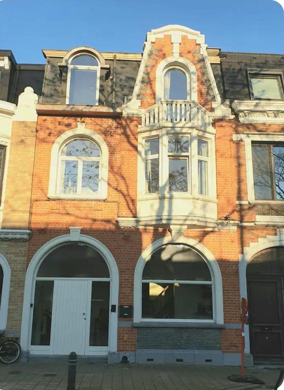 a brick building with white windows on a street at Mi casa es su casa in Ghent
