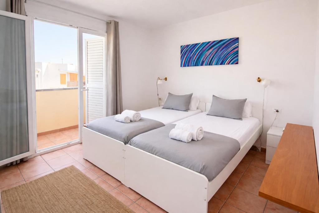 two beds in a white room with a window at The Tree House Coliving in El Médano