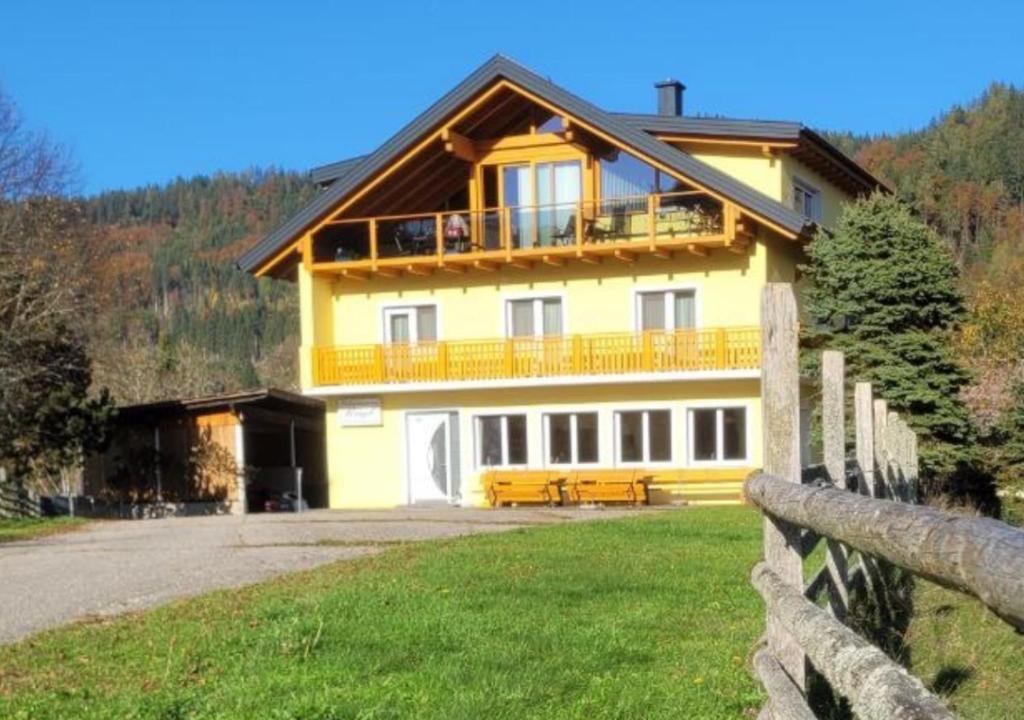 a yellow house with a fence in front of it at Apartment mit Balkon & Bergblick inklusive Parkplatz in Christofberg
