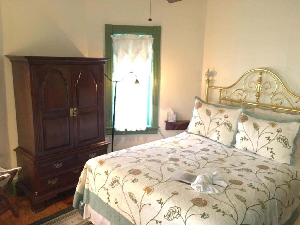 a bedroom with a bed and a dresser and a window at Parsonage Inn Bed and Breakfast in Saint Michaels