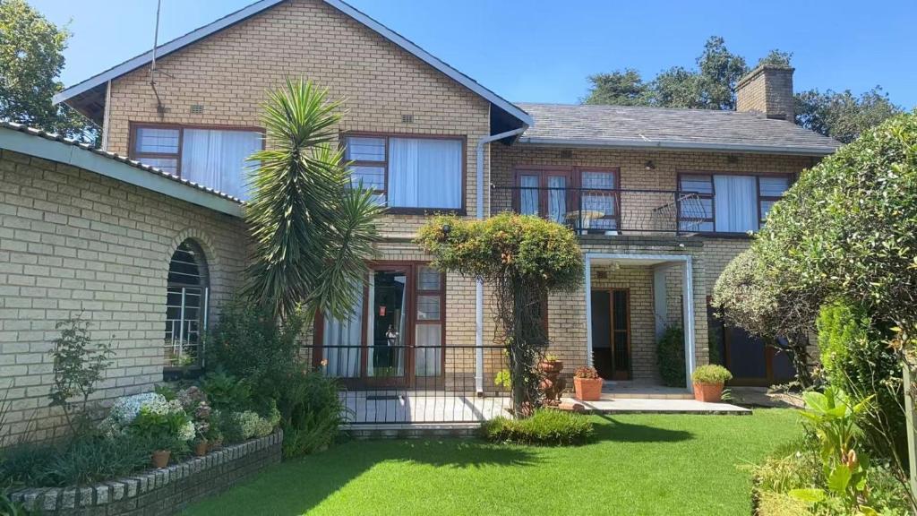 a brick house with a palm tree in the yard at Lens BnB Guesthouse in Benoni