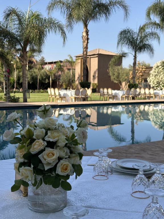 a table with a vase of flowers on a table with a pool at Fekhara CC in Marrakesh