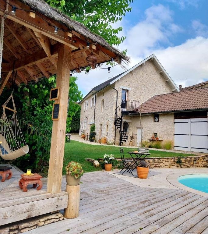 a wooden deck with a pergola next to a house at L'Armandine in Saint-Marcel-Bel-Accueil