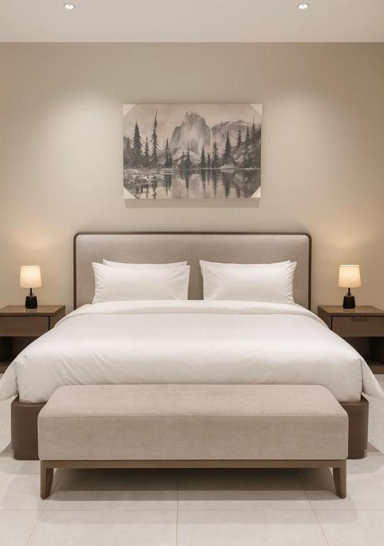 a bedroom with a large white bed with two lamps at Riwaq suite in Jeddah