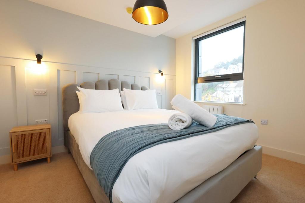 a bedroom with a large white bed with a window at The Central Swansea Hall 1BR Apartment in Swansea