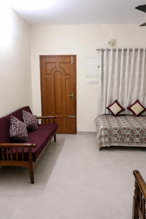 a living room with a couch and a wooden door at Zest Homes Nugambakkam in Chennai