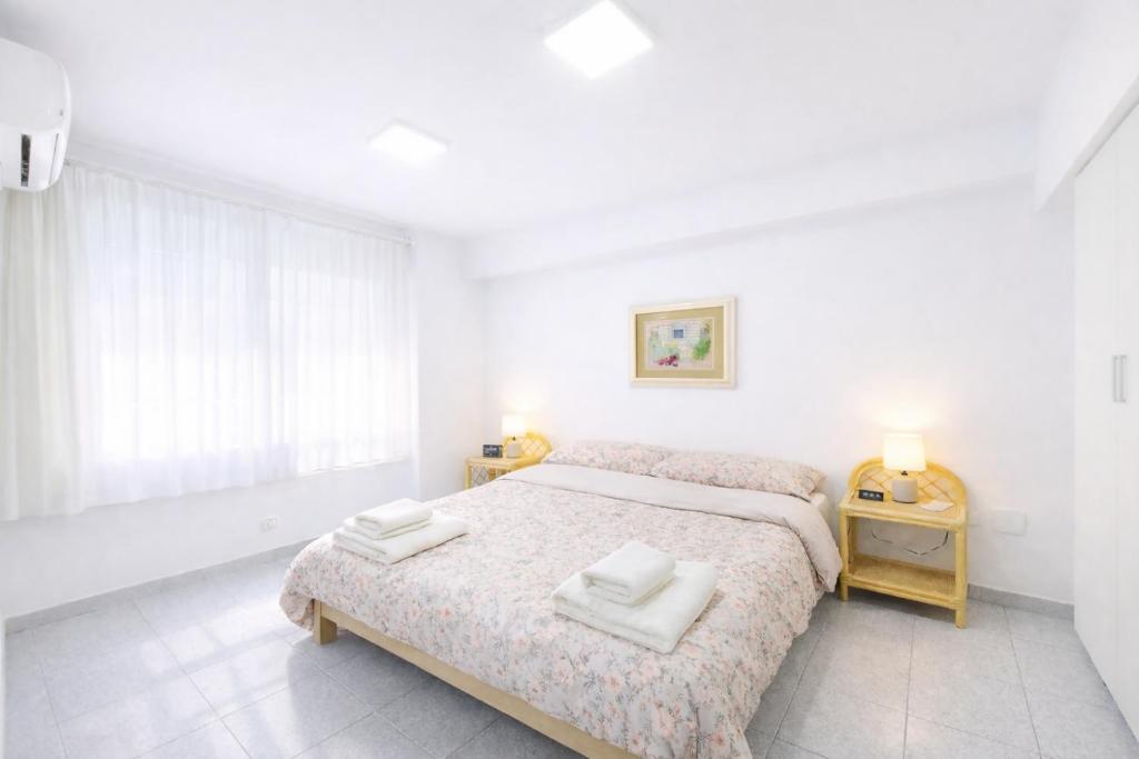 a white bedroom with a bed with towels on it at Alojamiento San Juan en Murcia Centro in Murcia