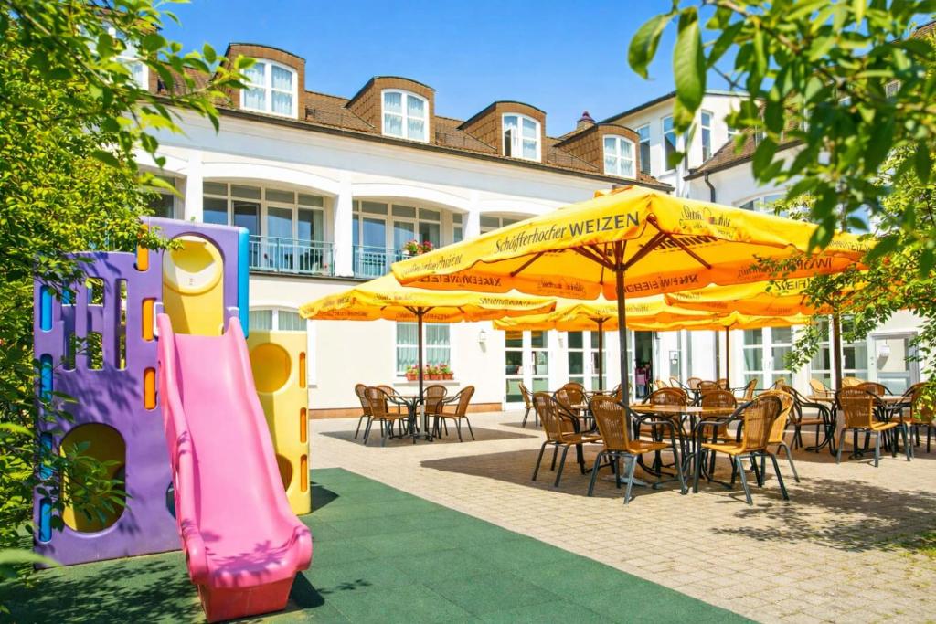 a restaurant with a inflatable slide and tables and umbrellas at Hotel Goldener Fasan in Oranienbaum-Wörlitz