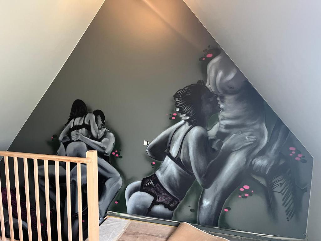 ein Zimmer mit einer Wand, an der ein Wandgemälde von zwei Frauen zu sehen ist in der Unterkunft Cachoire in Tournai
