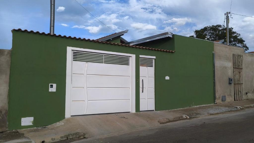 a green building with two white garage doors at Canastra House in Delfinópolis