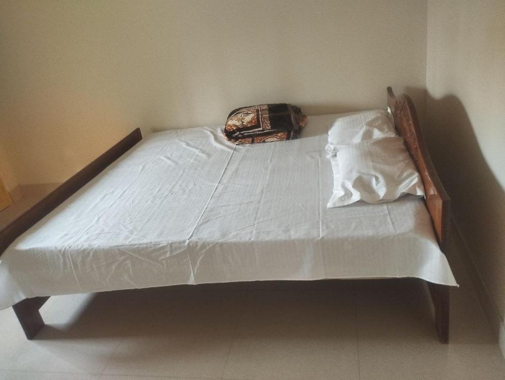 ein Bett mit weißen Laken und einer Tasche darauf in der Unterkunft Shriji in mayapur