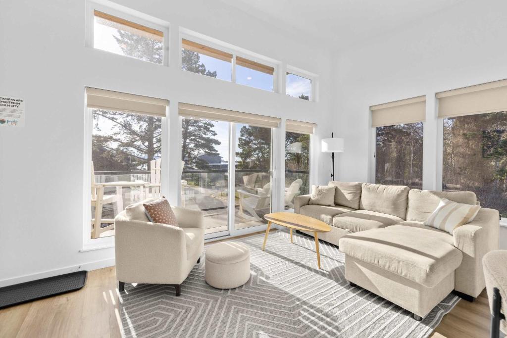 a living room with white furniture and large windows at Bay View Loft in Lincoln City