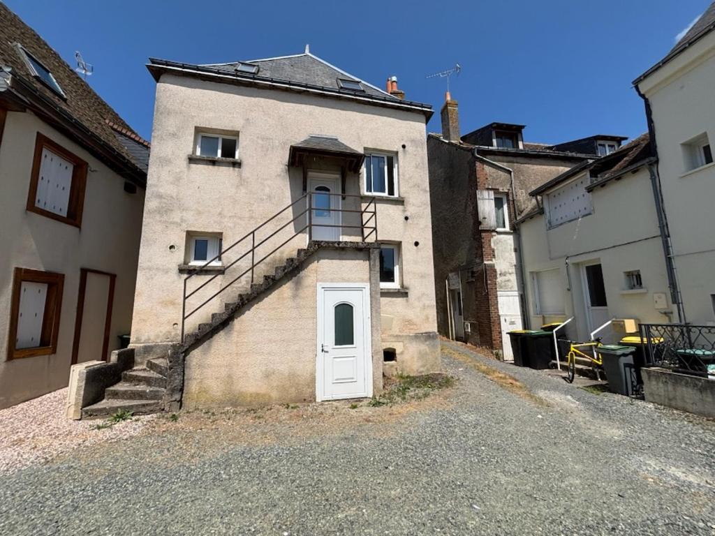 an old building with a white door and stairs at Appartement Numéro 3, centre chateau-renault in Château-Renault