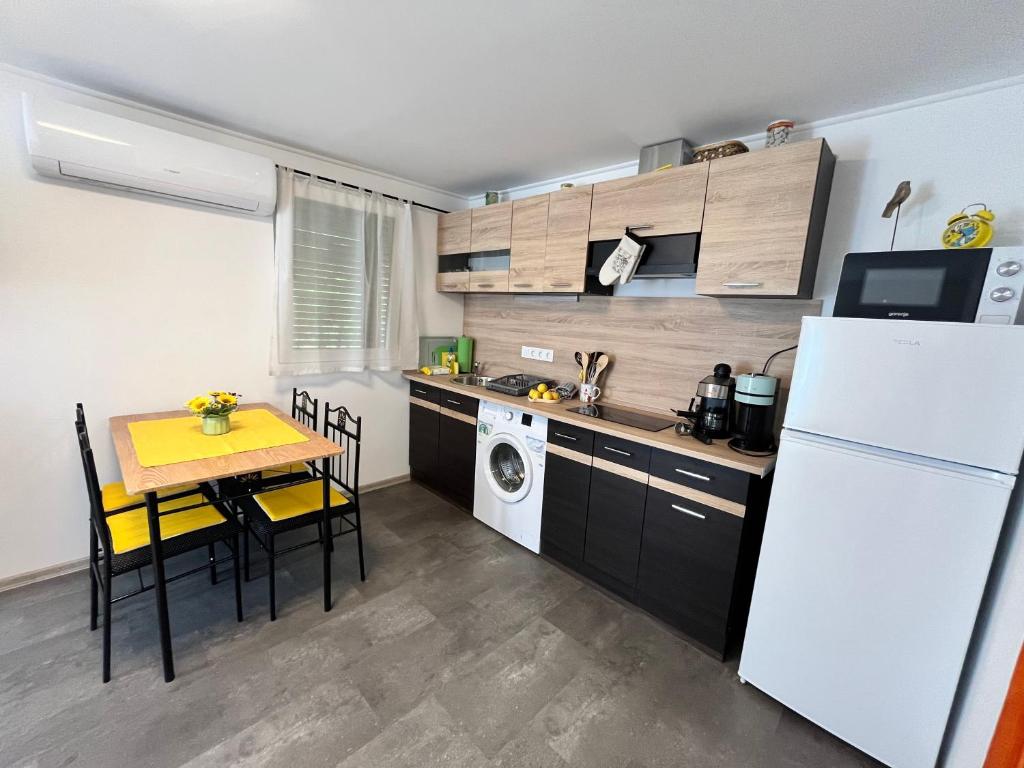 a small kitchen with a table and a white refrigerator at Kicsi Rigó Nyaralóház in Lakitelek