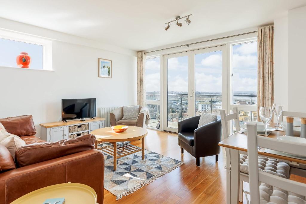 a living room with a couch and a table at A Wave From It All - Extensive Harbour Views from Wrap-Around Balcony in Poole
