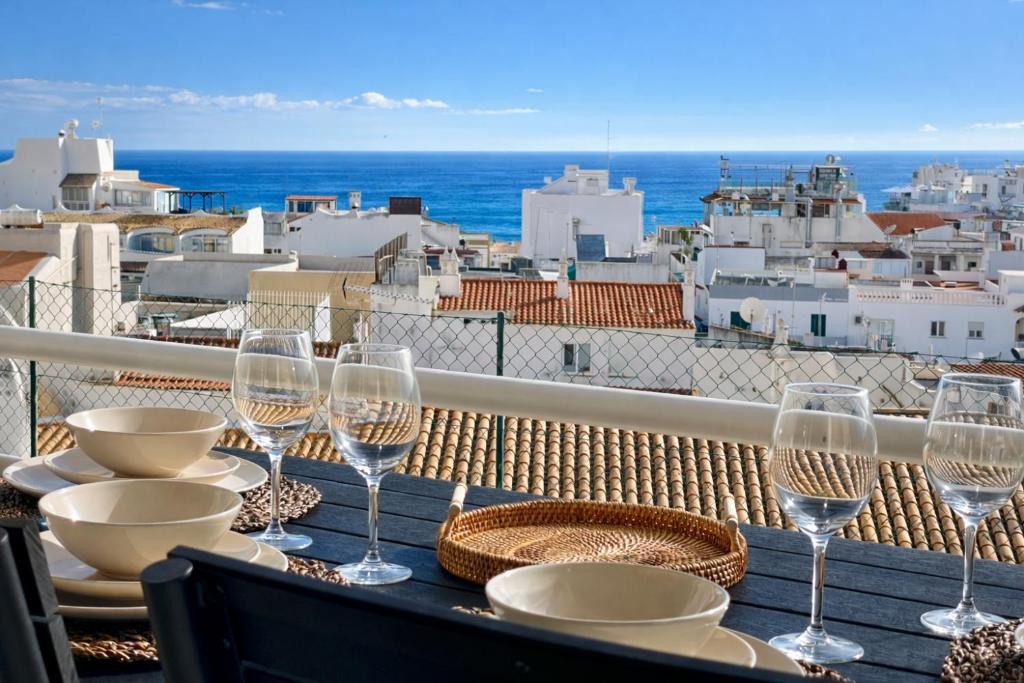 a table with wine glasses and a view of the ocean at RosaMar apartment sea view and pool in Albufeira