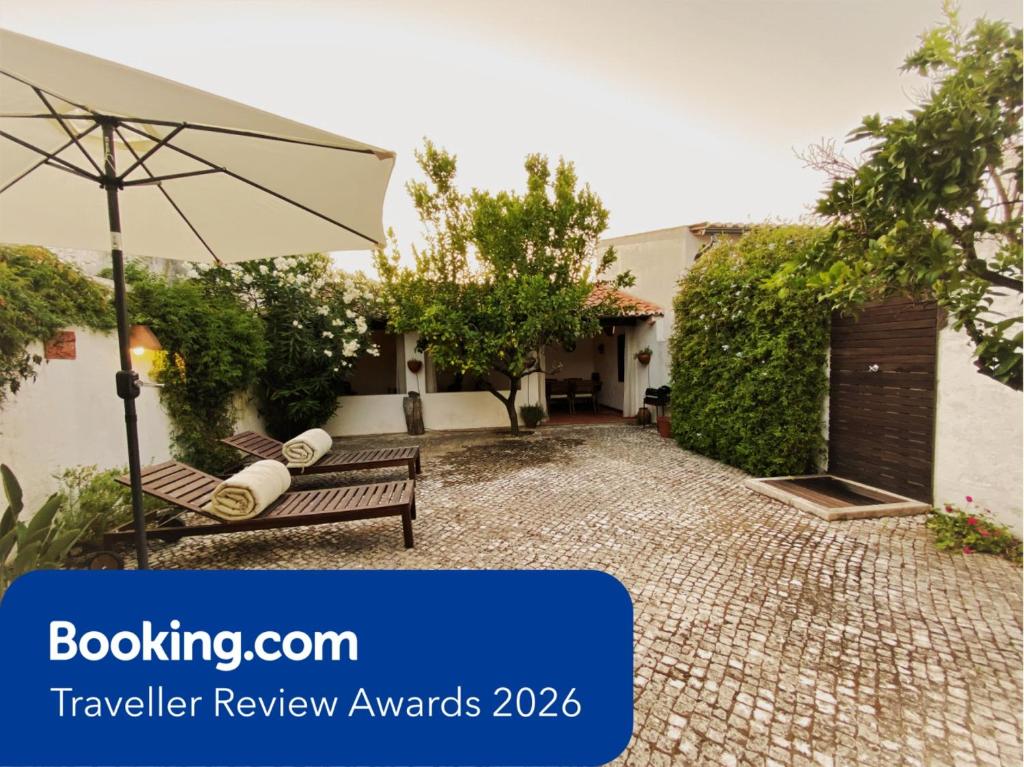 a patio with a bench and an umbrella at Casa da Galega in Golegã