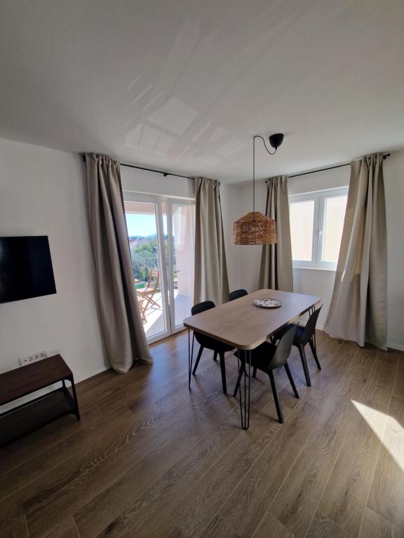 a dining room with a table and chairs and windows at Apartmani Tribunj Cvitan in Tribunj