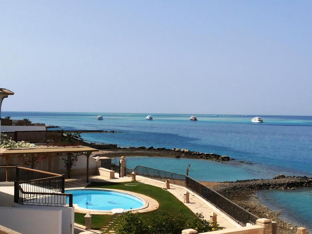 a swimming pool next to a body of water at Hurghada Beach House in Hurghada